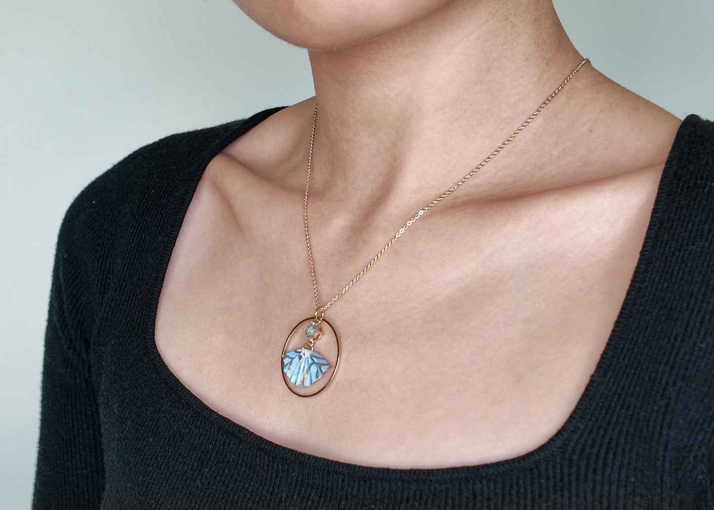 blue and gold origami fan necklace on model