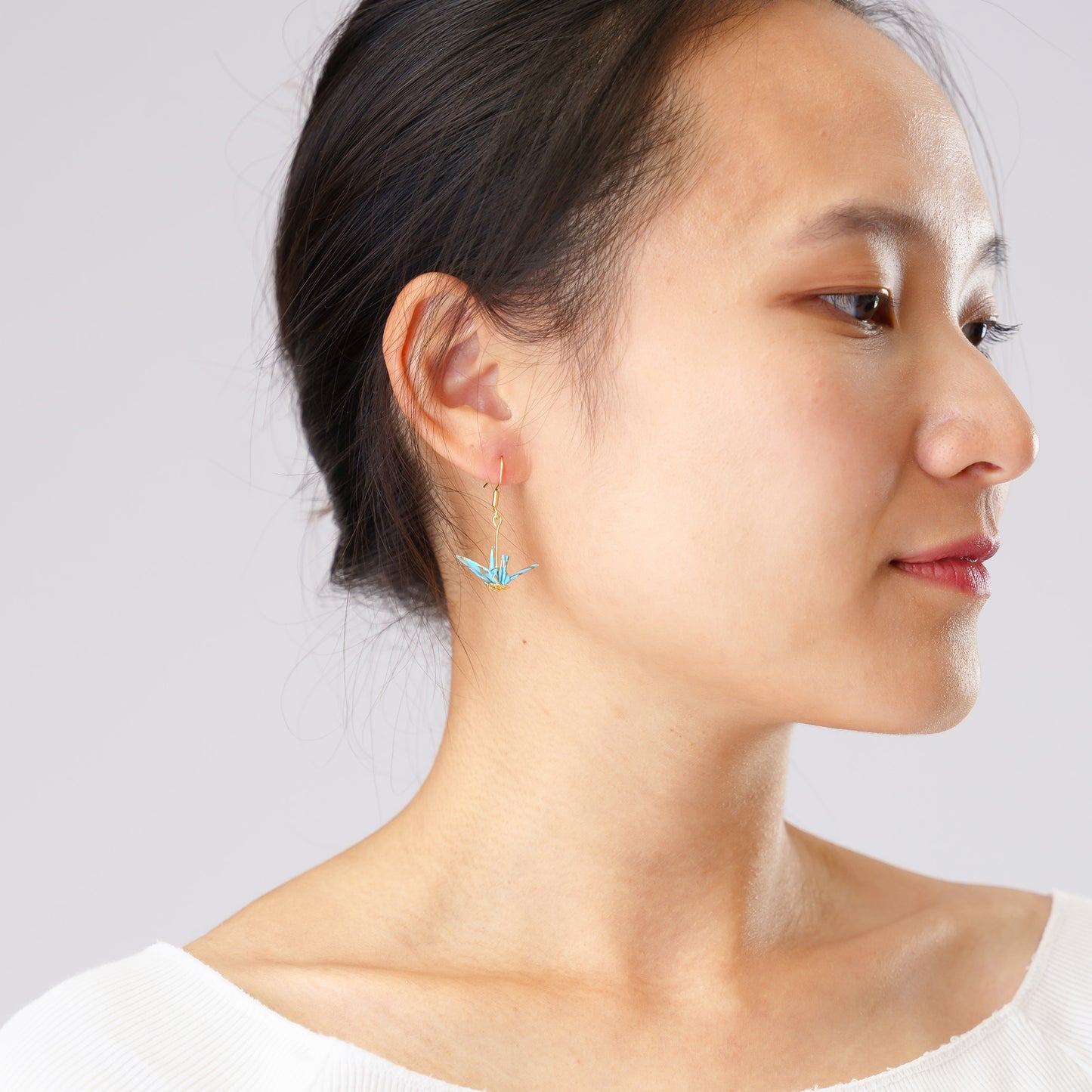 tiny origami crane earrings on model