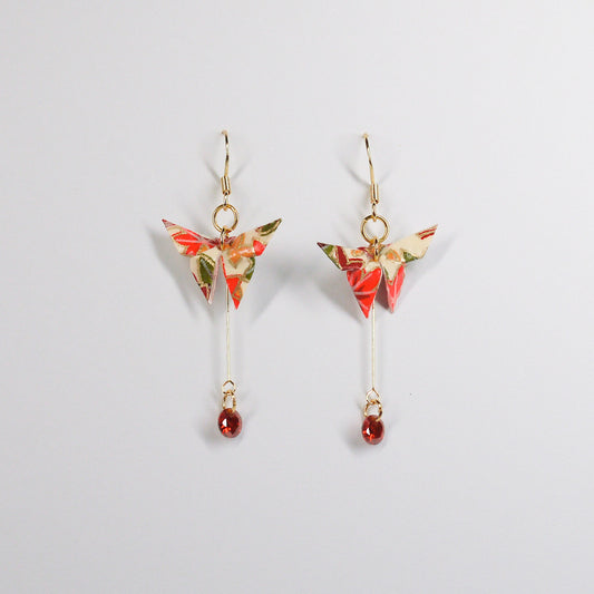 A pair of origami butterfly earrings with gold hooks and red dangling crystals.