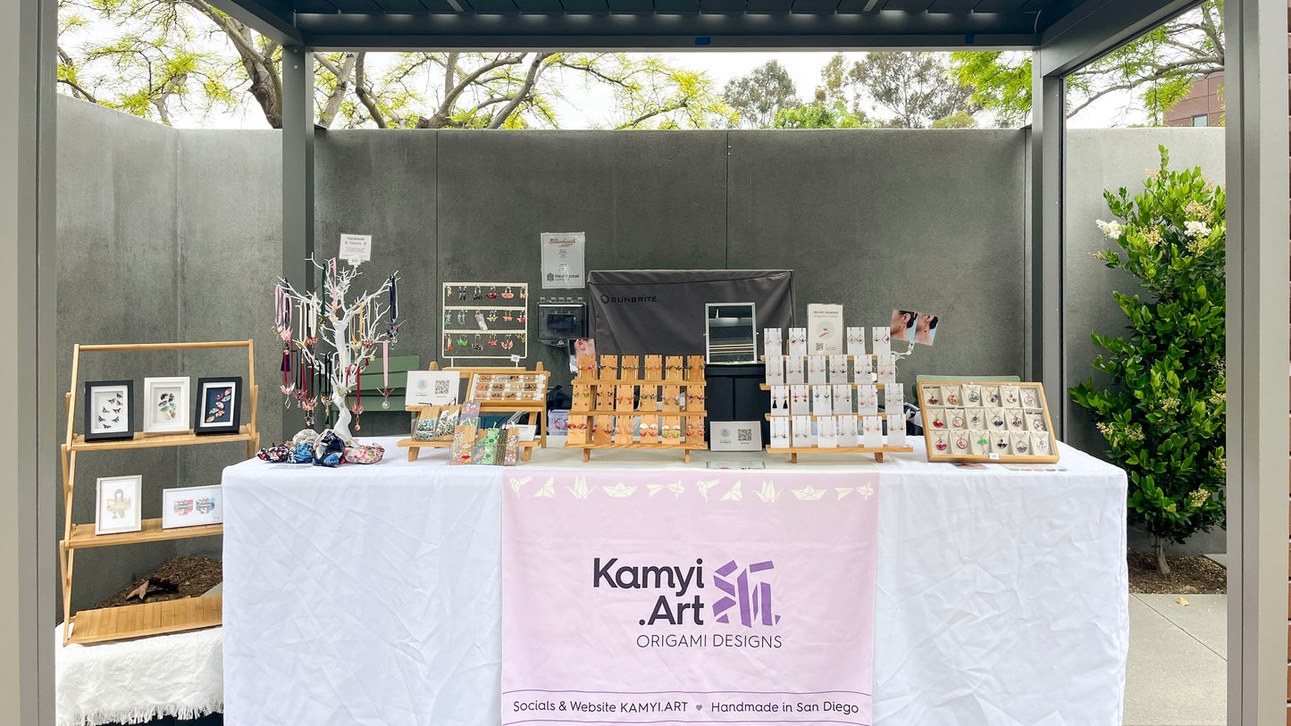Karnyi Art booth with various products on a table outdoors