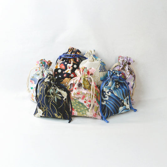 mystery bags of origami jewelry. Set of colorful drawstring bags with floral patterns on a white background