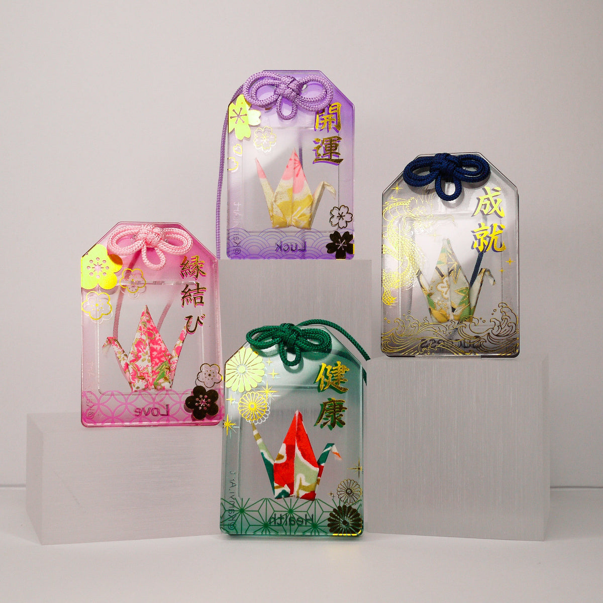 Four decorative omamori with colorful designs and text on a white background