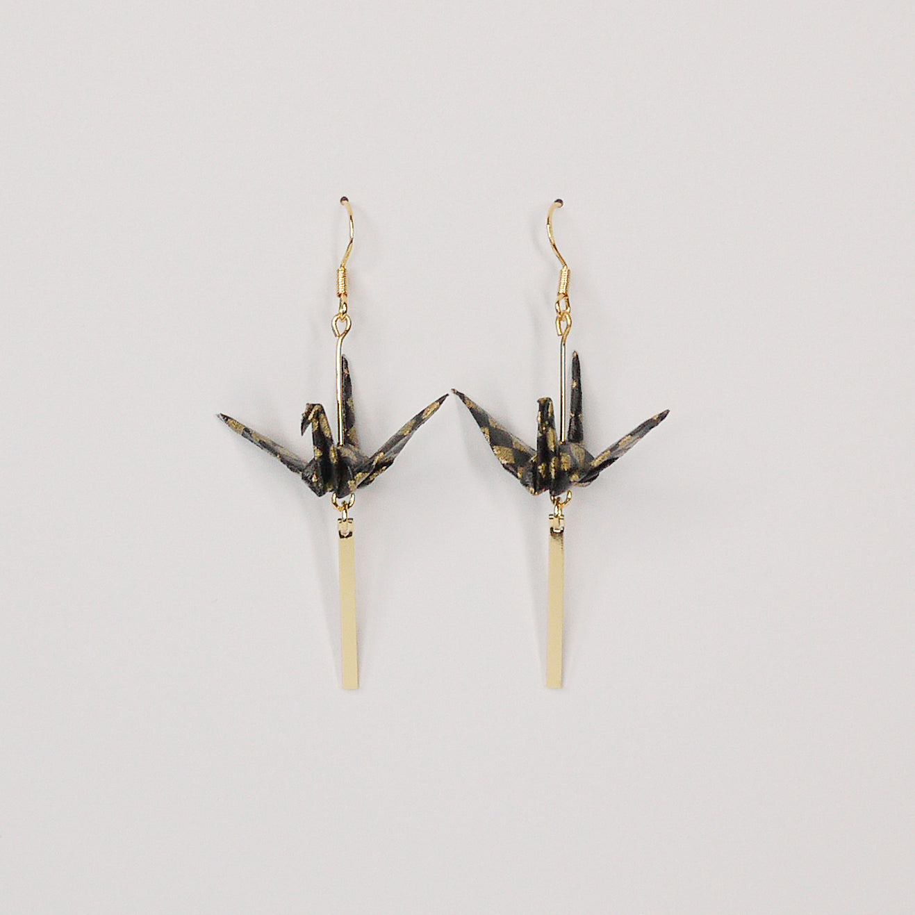 Pair of handmade black origami crane earrings with gold checkered print, gold bar and hooks, crafted from traditional Japanese washi paper. front view