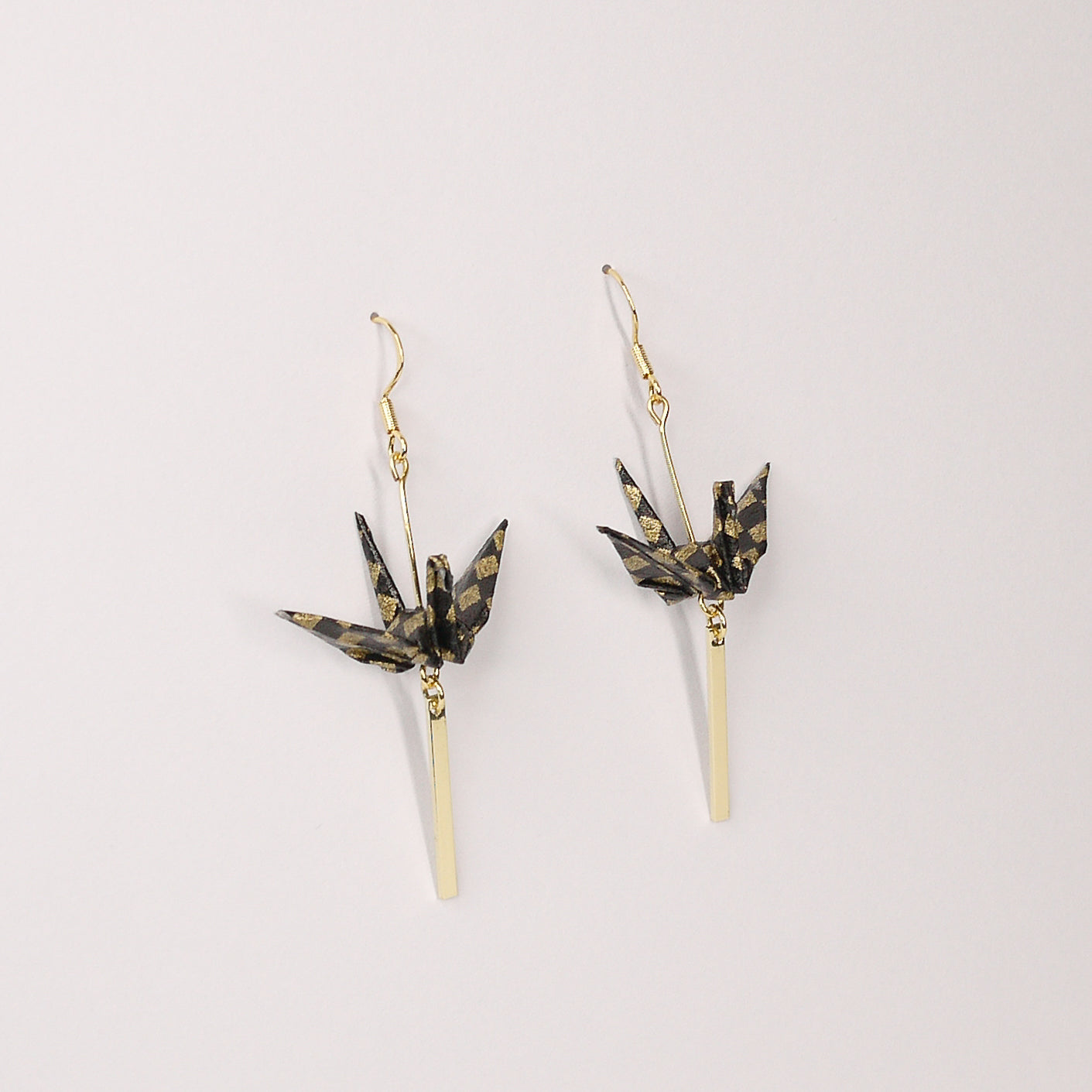 Pair of handmade black origami crane earrings with gold checkered print, gold bar and hooks, crafted from traditional Japanese washi paper. main view