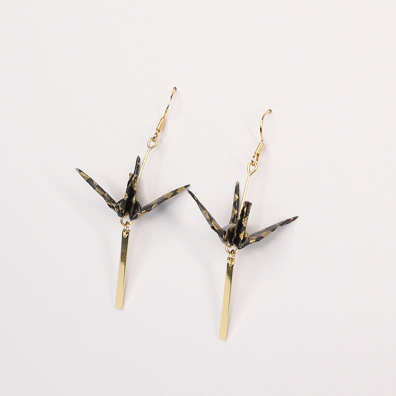 Pair of handmade black origami crane earrings with gold checkered print, gold bar and hooks, crafted from traditional Japanese washi paper. side view