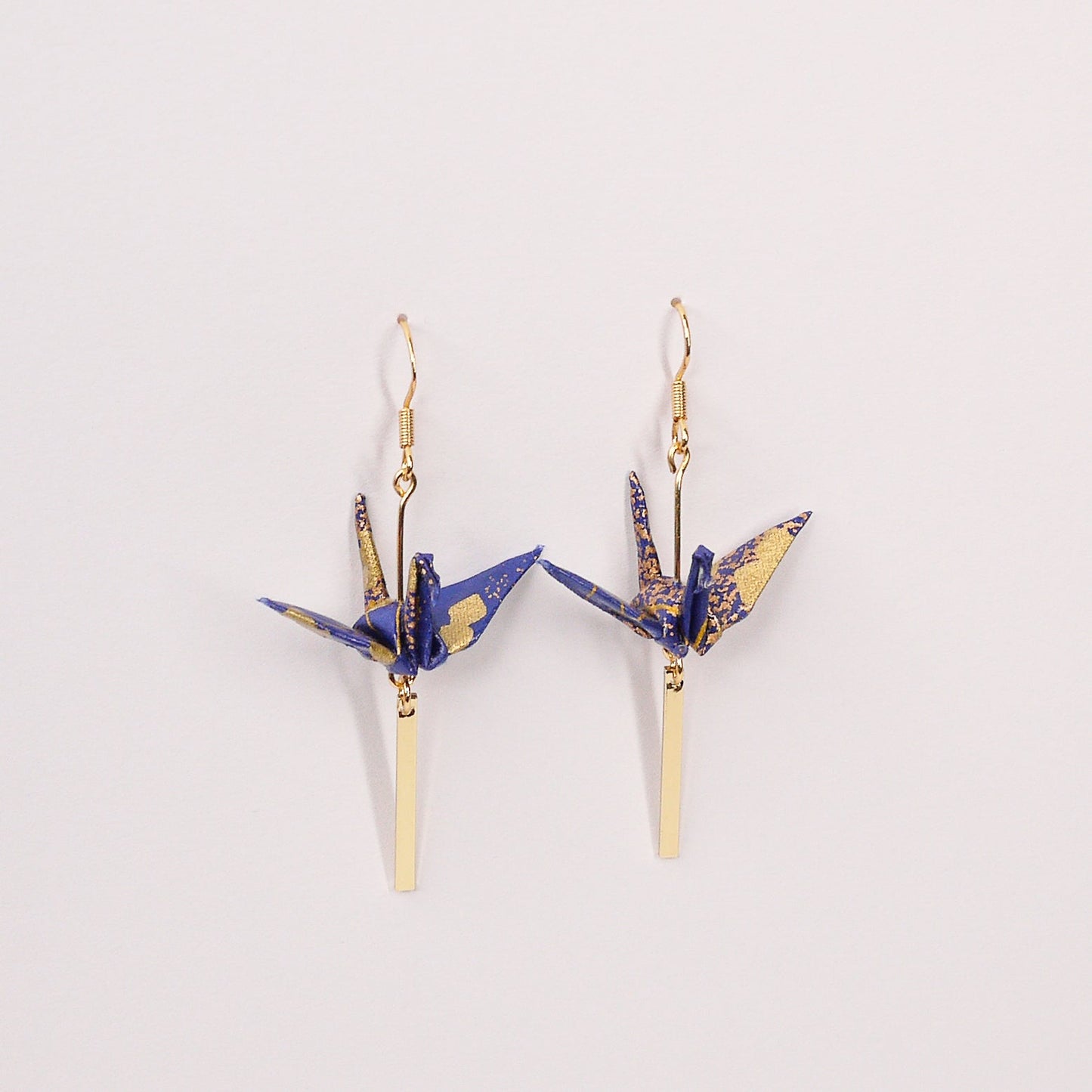 Pair of handmade black origami crane earrings with gold checkered print, gold bar and hooks, crafted from traditional Japanese washi paper. top view