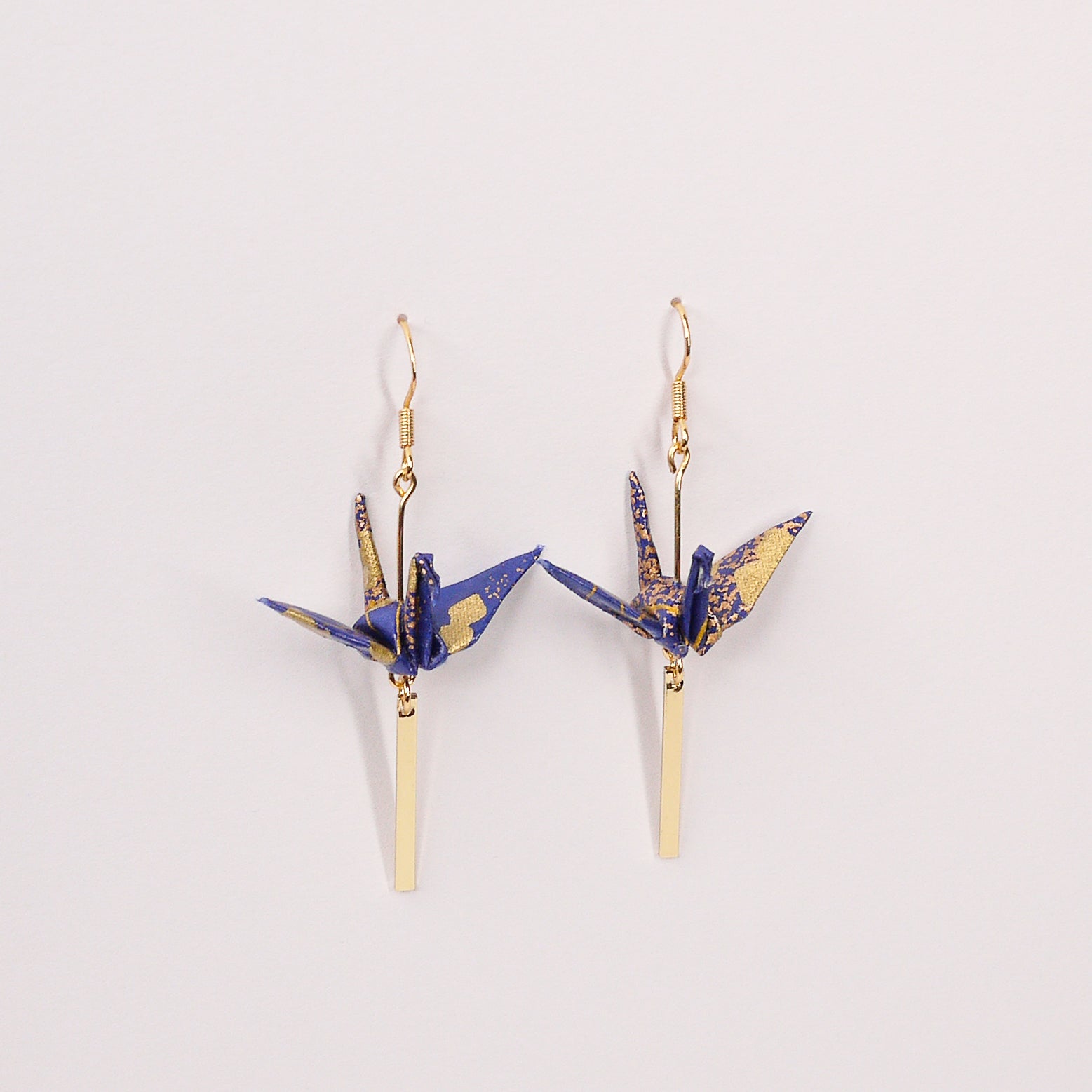 Pair of handmade black origami crane earrings with gold checkered print, gold bar and hooks, crafted from traditional Japanese washi paper. top view