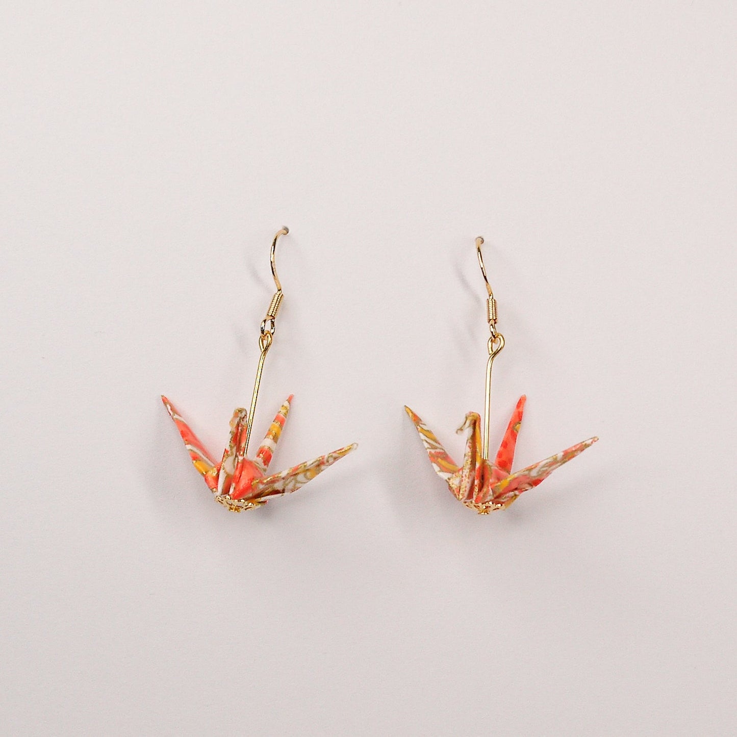 Pair of handmade orange origami crane earrings with chrysanthemum floral print and gold hooks, crafted from traditional Japanese washi paper. front view