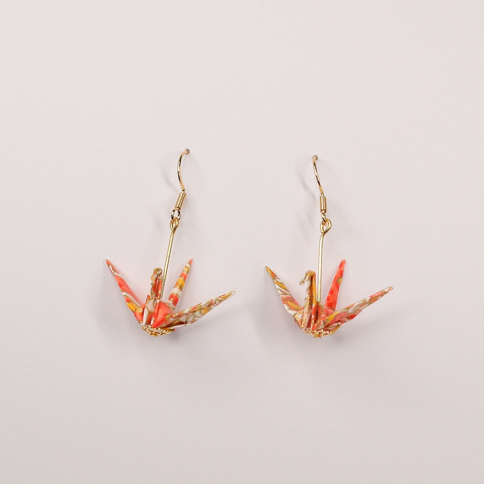 Pair of handmade orange origami crane earrings with chrysanthemum floral print and gold hooks, crafted from traditional Japanese washi paper. front view