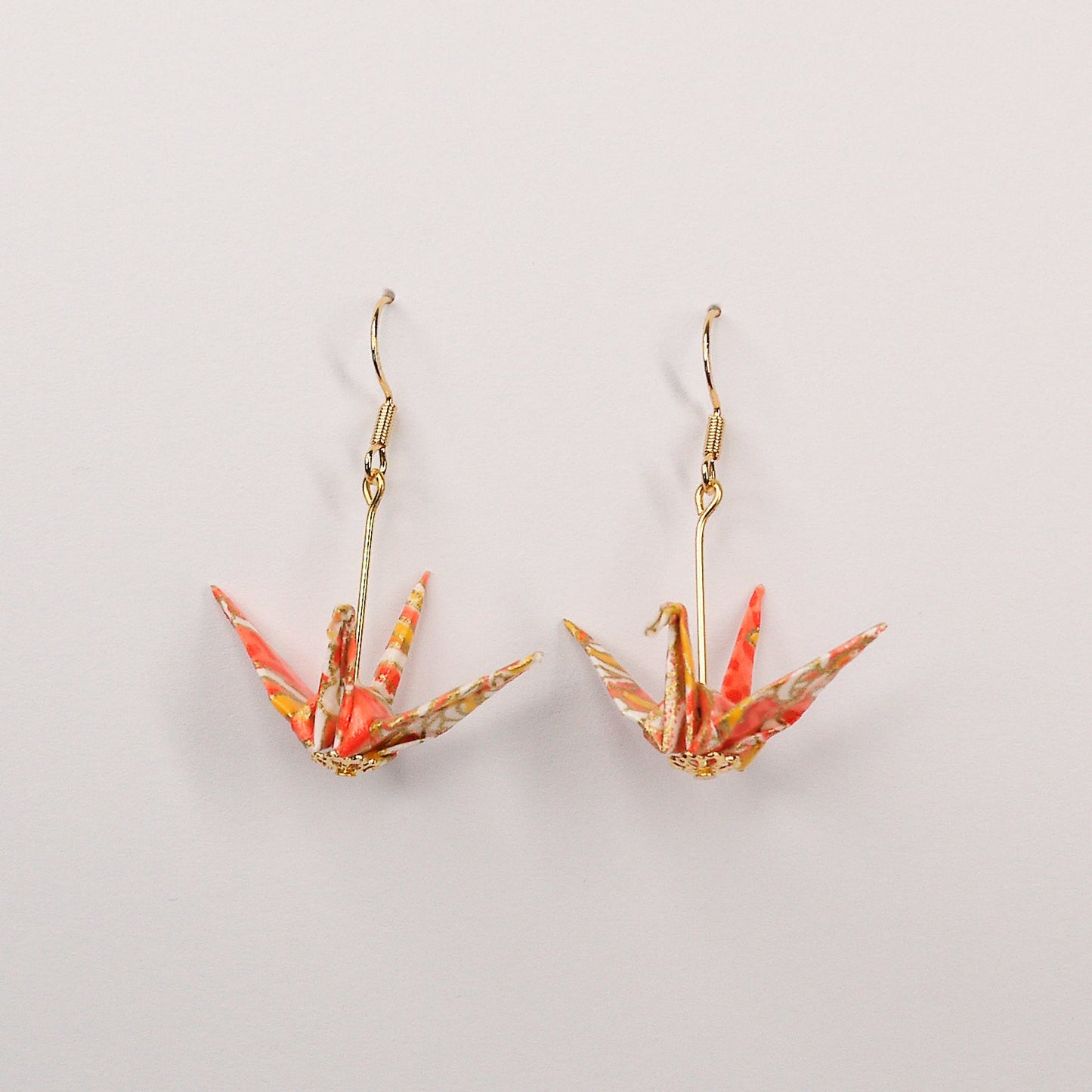 Pair of handmade orange origami crane earrings with chrysanthemum floral print and gold hooks, crafted from traditional Japanese washi paper. main view