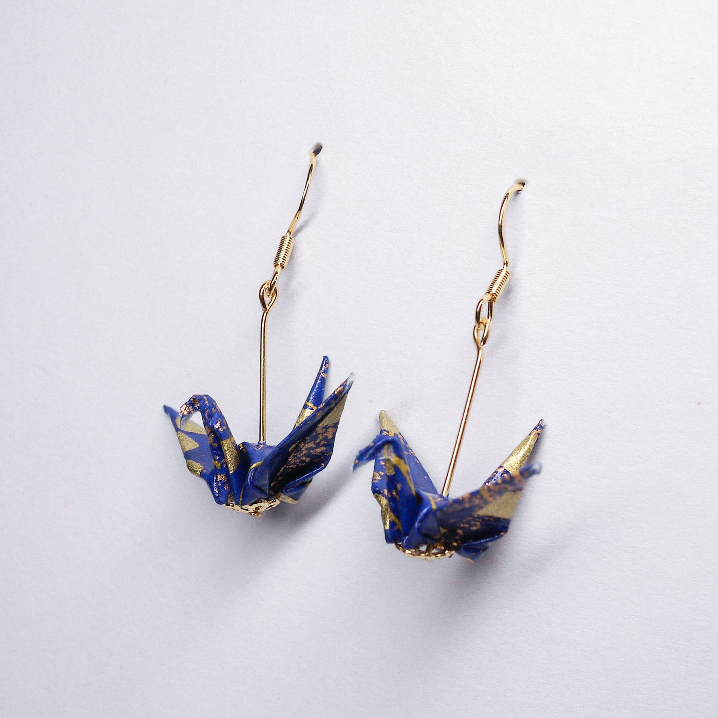 Pair of handmade royal blue origami crane earrings with gold cloud, crafted from traditional Japanese washi paper. side view