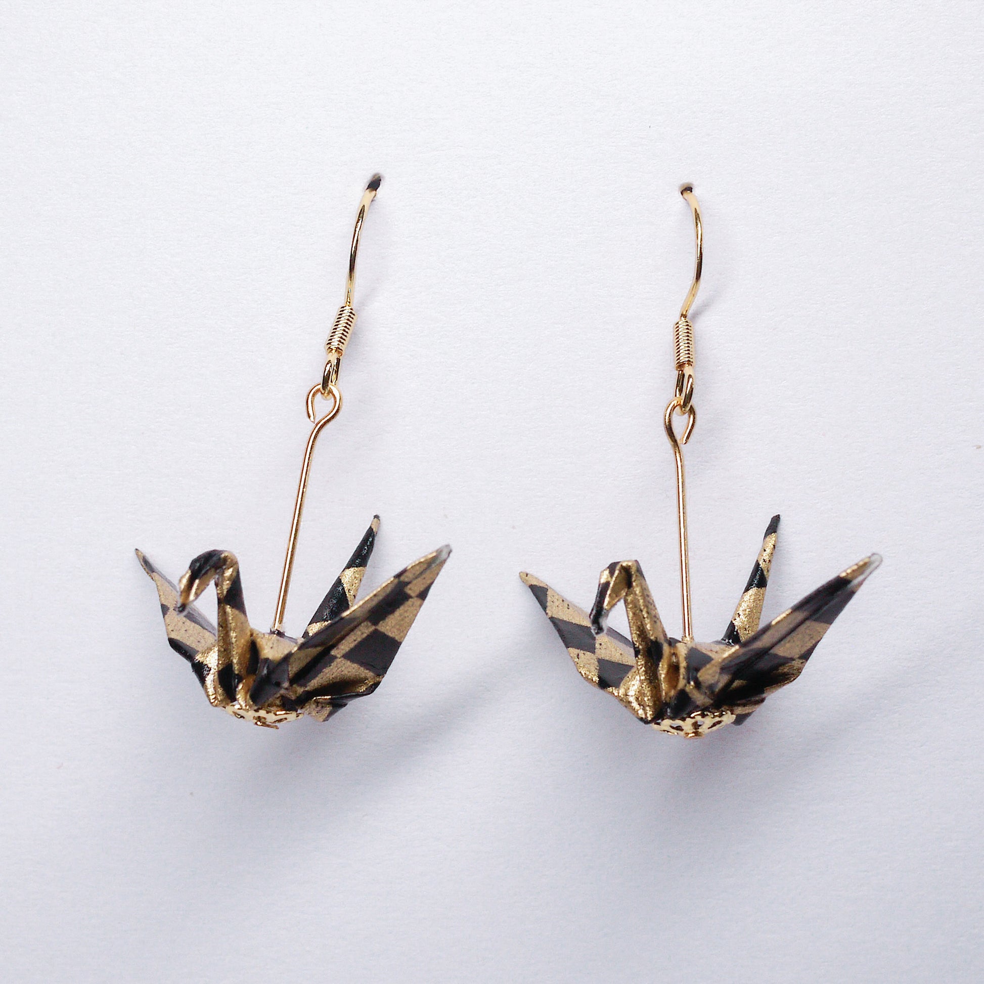 Pair of handmade black origami crane earrings with gold checks, crafted from traditional Japanese washi paper. front view