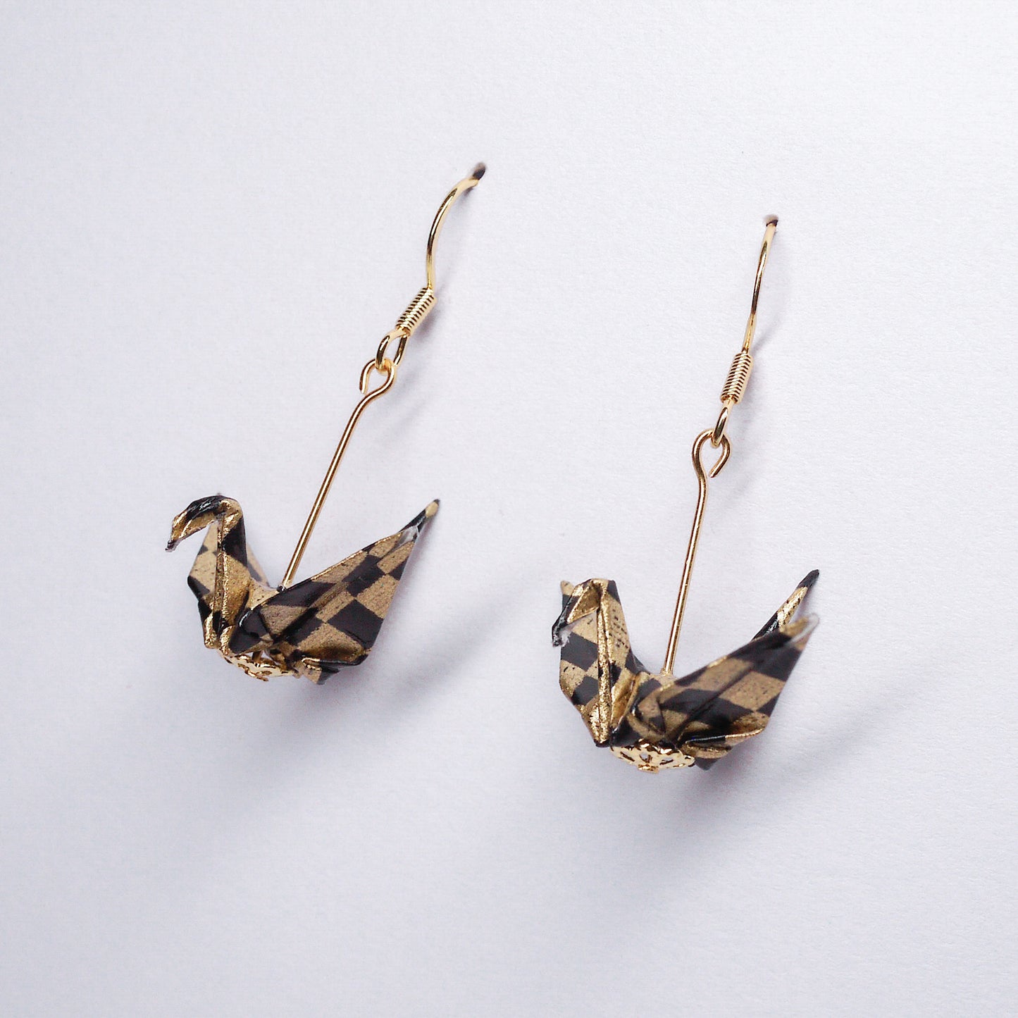 Pair of handmade black origami crane earrings with gold checks, crafted from traditional Japanese washi paper. side view