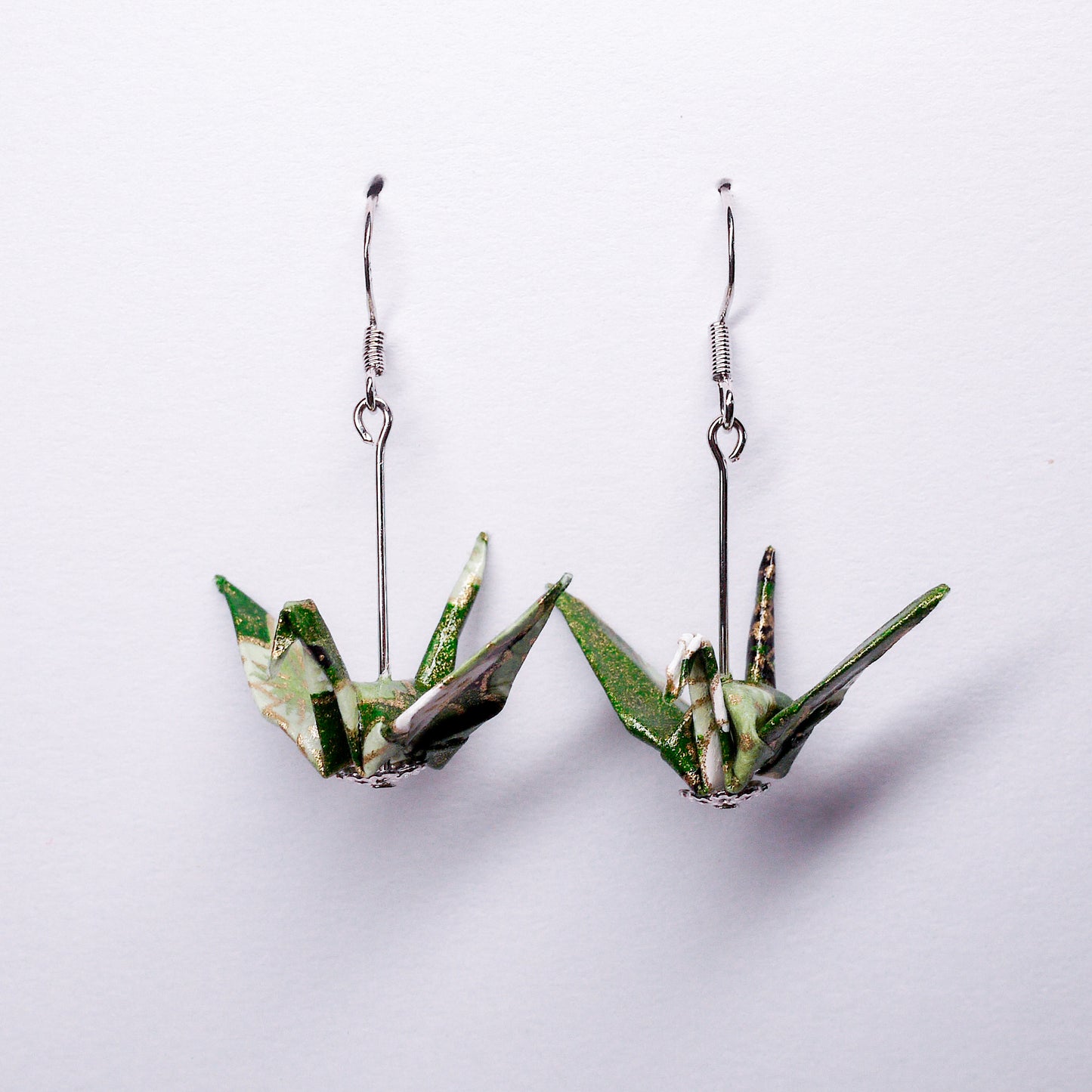 Pair of handmade green origami crane earrings with flower prints and hooks, crafted from traditional Japanese washi paper. front view