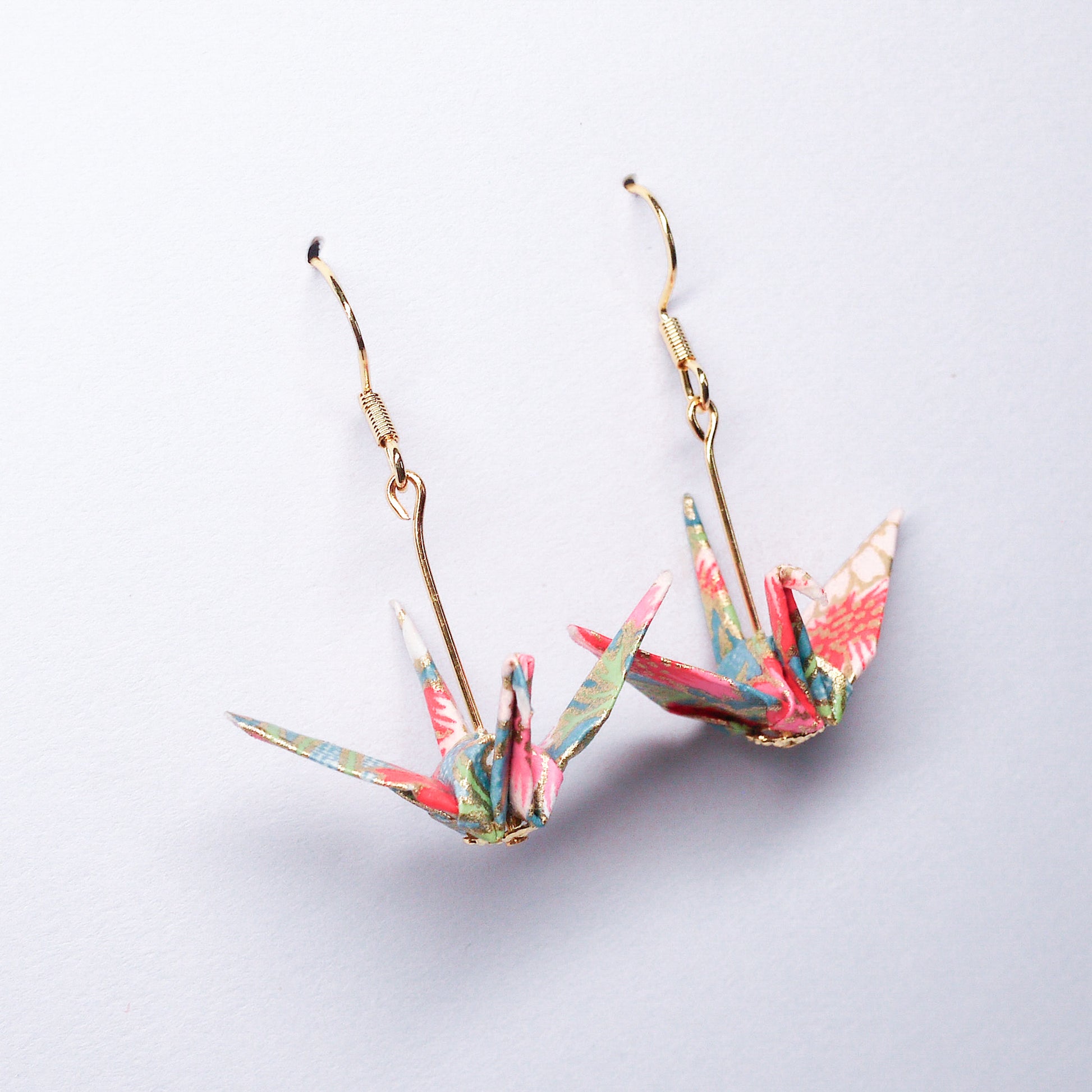 Pair of handmade blue origami crane earrings with pink flowers and hooks, crafted from traditional Japanese washi paper. side view