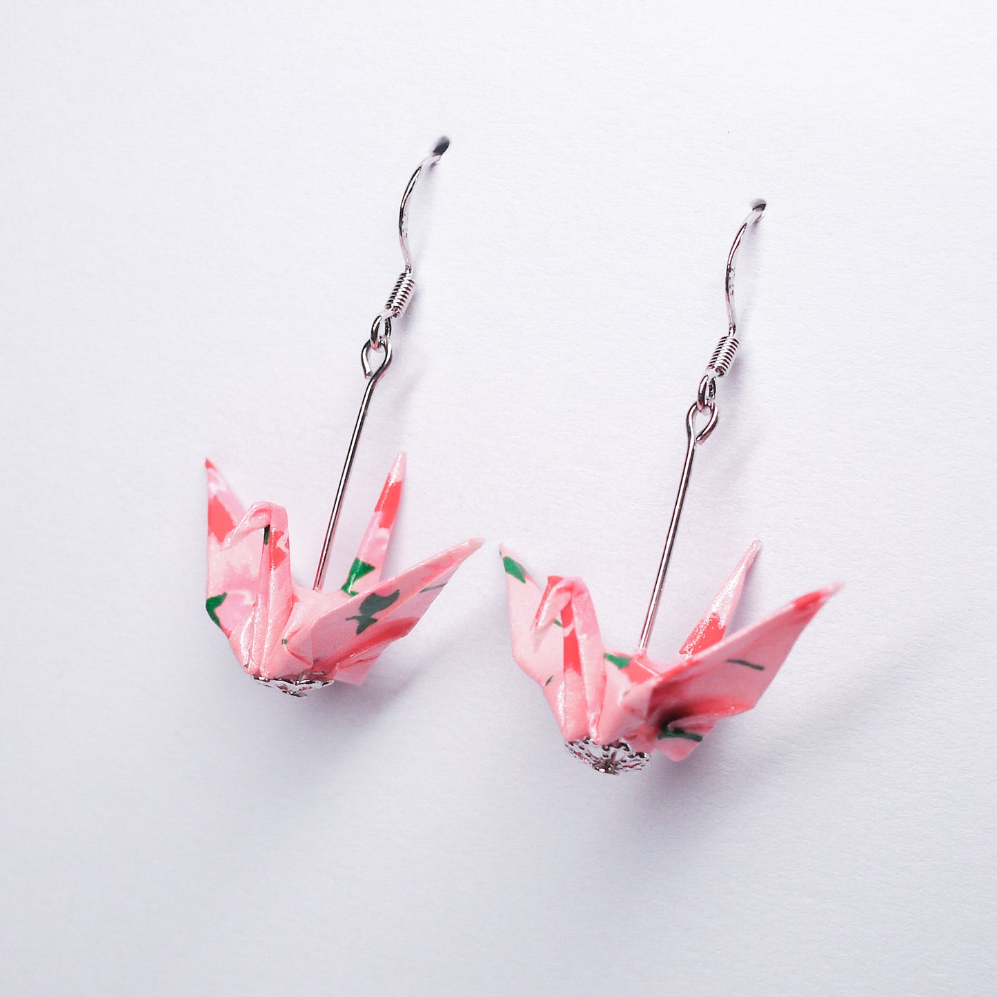 Pair of handmade pink origami crane earrings with pink flower prints and hooks, crafted from traditional Japanese washi paper. side view