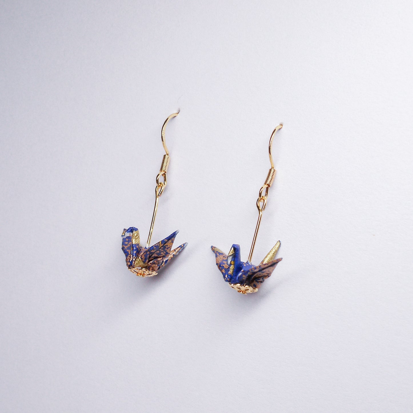 Pair of handmade blue origami crane earrings with gold accents and hooks, crafted from traditional Japanese washi paper. side