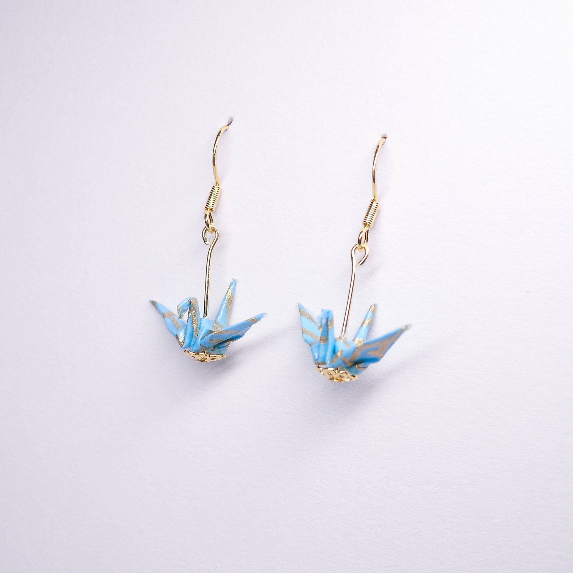 Pair of handmade teal origami crane earrings with gold waves and hooks, crafted from traditional Japanese washi paper. side view