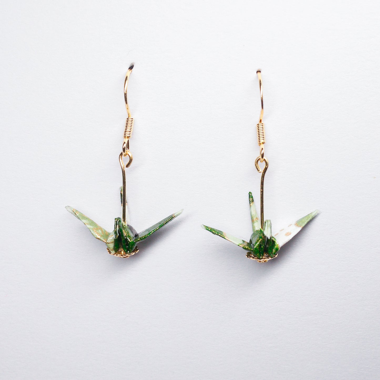 Pair of handmade green origami crane earrings with flower prints and hooks, crafted from traditional Japanese washi paper. front view