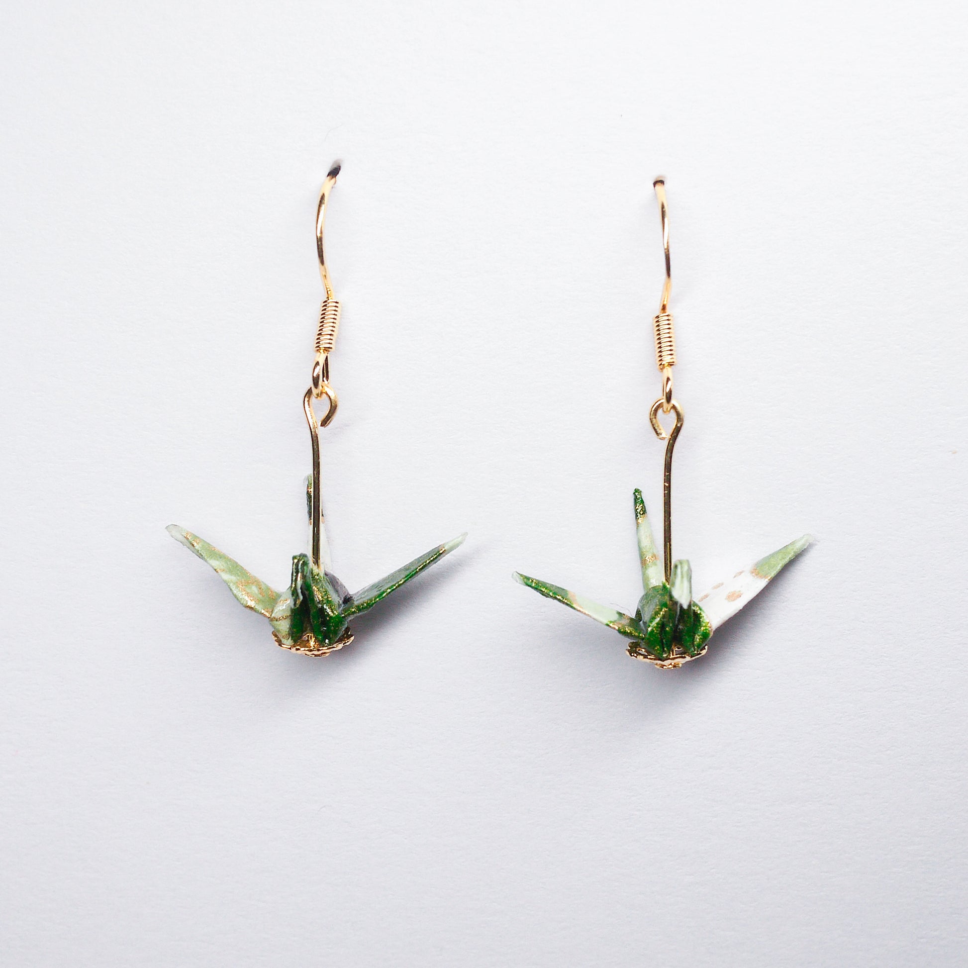 Pair of handmade green origami crane earrings with flower prints and hooks, crafted from traditional Japanese washi paper. front view