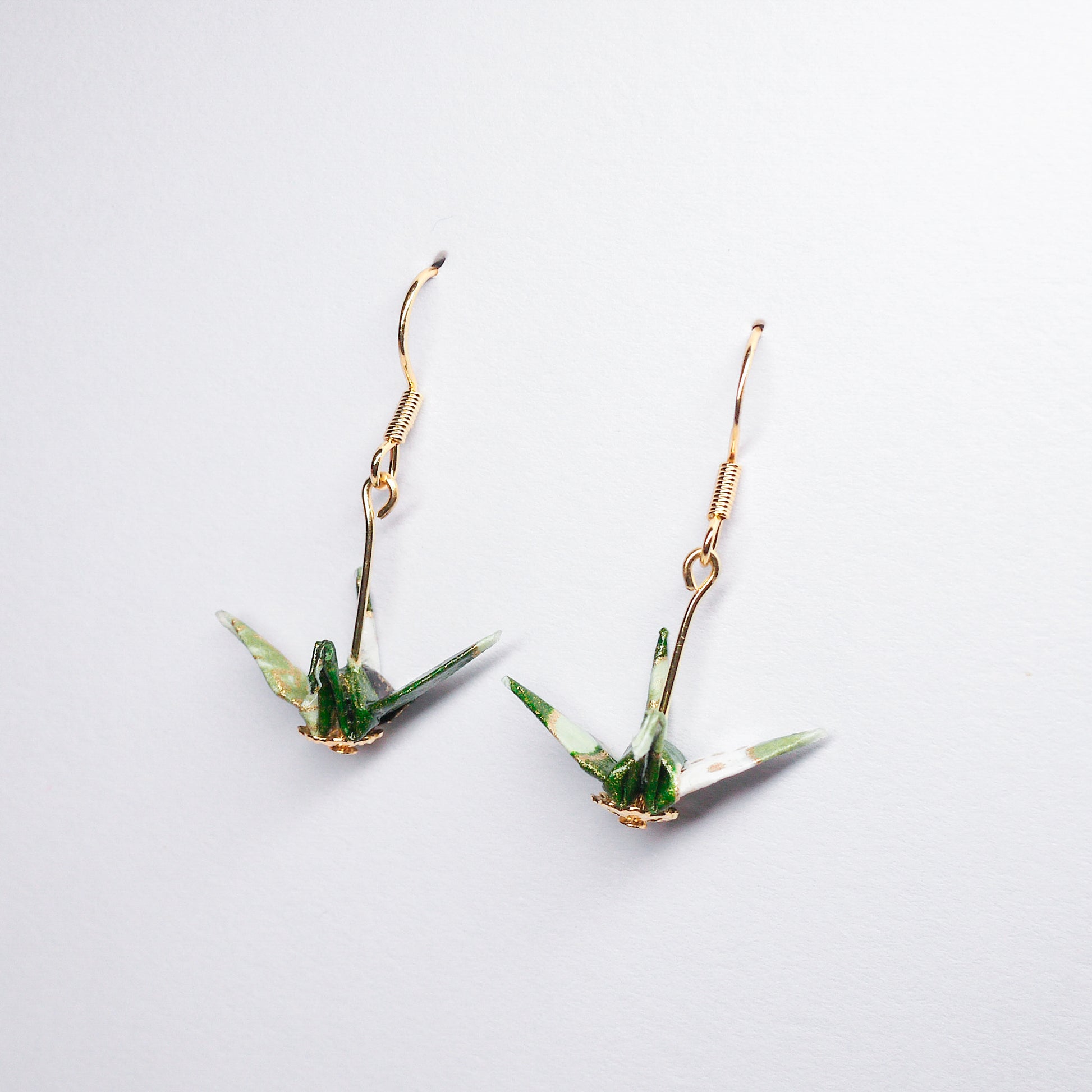 Pair of handmade green origami crane earrings with flower prints and hooks, crafted from traditional Japanese washi paper. side view