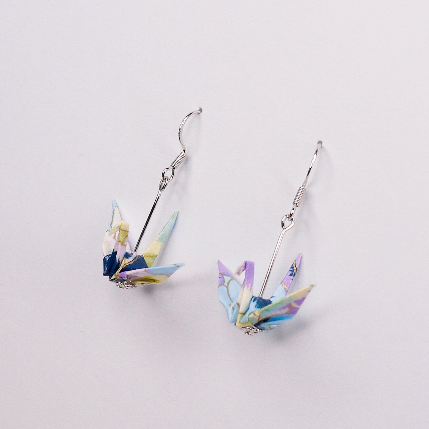 Pair of handmade purple and blue origami crane earrings with pansy floral print and silver hooks, crafted from traditional Japanese washi paper. main view