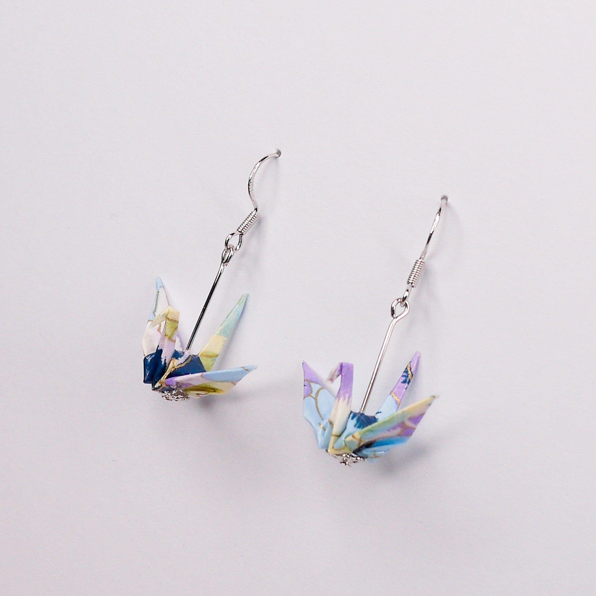 Pair of handmade purple and blue origami crane earrings with pansy floral print and silver hooks, crafted from traditional Japanese washi paper. main view