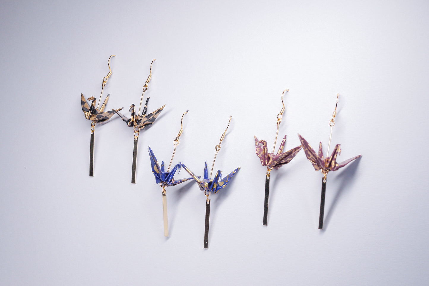 Collection of handmade origami crane earrings in various colors, featuring gold hooks and delicate paper cranes crafted from traditional Japanese washi paper