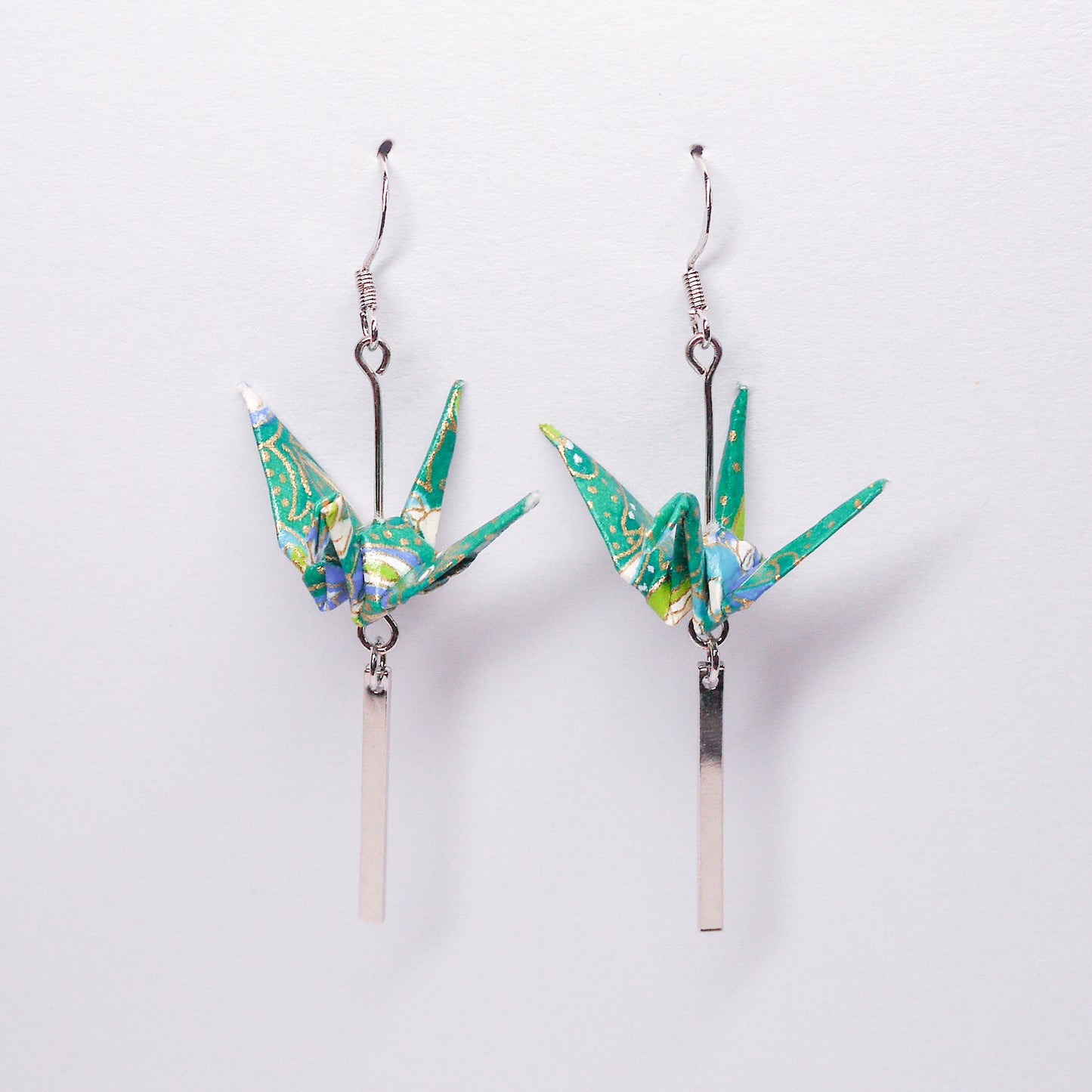 Pair of handmade green origami crane earrings with silver bar accents and hooks, crafted from traditional Japanese washi paper