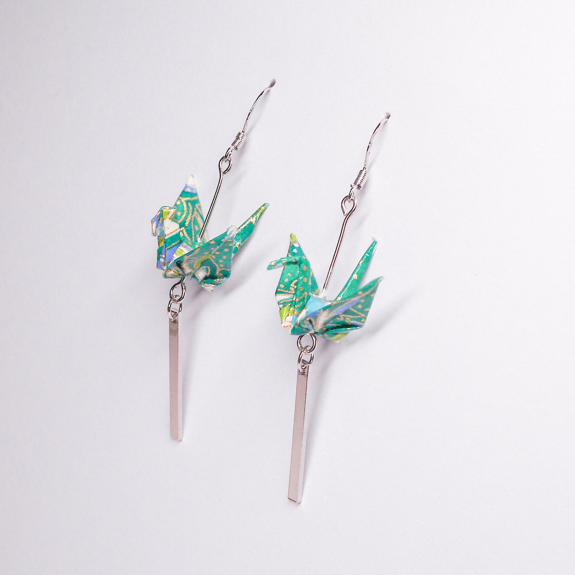 Pair of handmade green origami crane earrings with silver bar accents and hooks, crafted from traditional Japanese washi paper