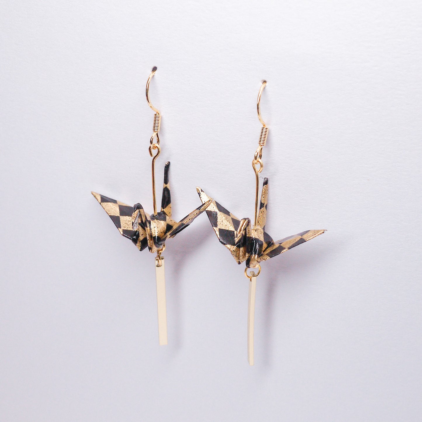 Pair of handmade black origami crane earrings with gold bar and hooks, crafted from traditional Japanese washi paper