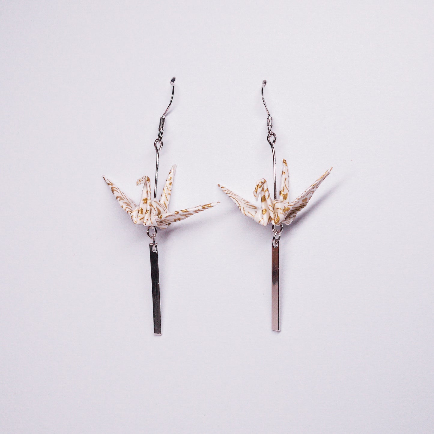 Pair of handmade white gold origami crane earrings with silver bar accents and hooks, crafted from traditional Japanese washi paper