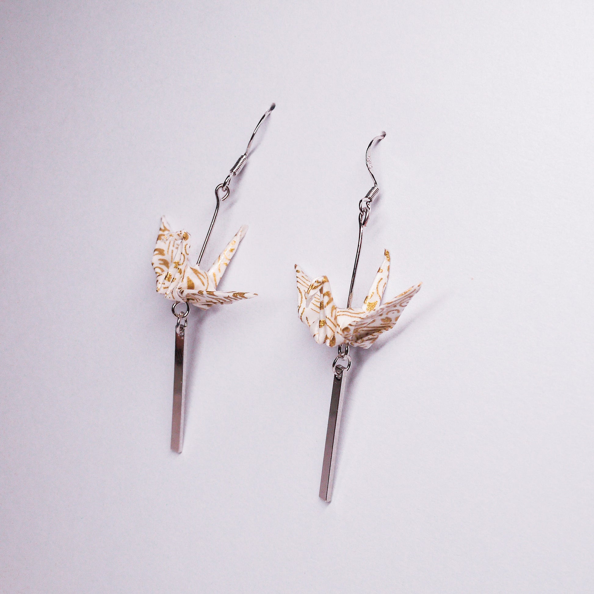 Pair of handmade white origami crane earrings with silver bar accents and hooks, crafted from traditional Japanese washi paper