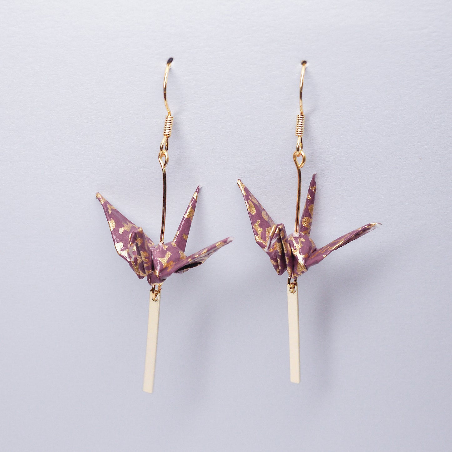 Pair of handmade purple origami crane earrings with gold bar and hooks, crafted from traditional Japanese washi paper