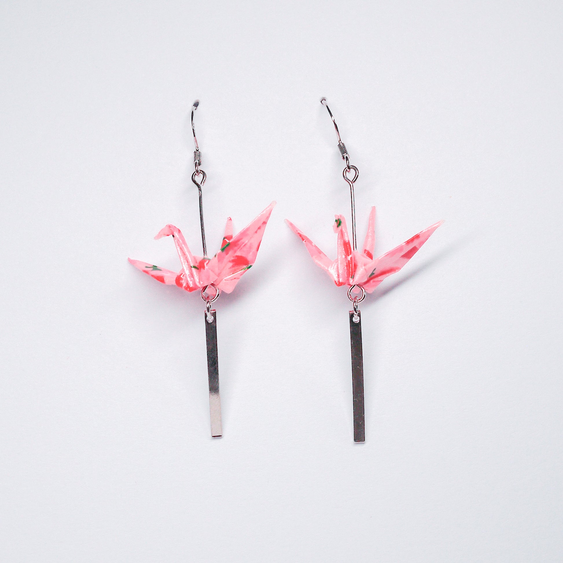 Pair of handmade pink origami crane earrings with silver bar accents and hooks, crafted from traditional Japanese washi paper