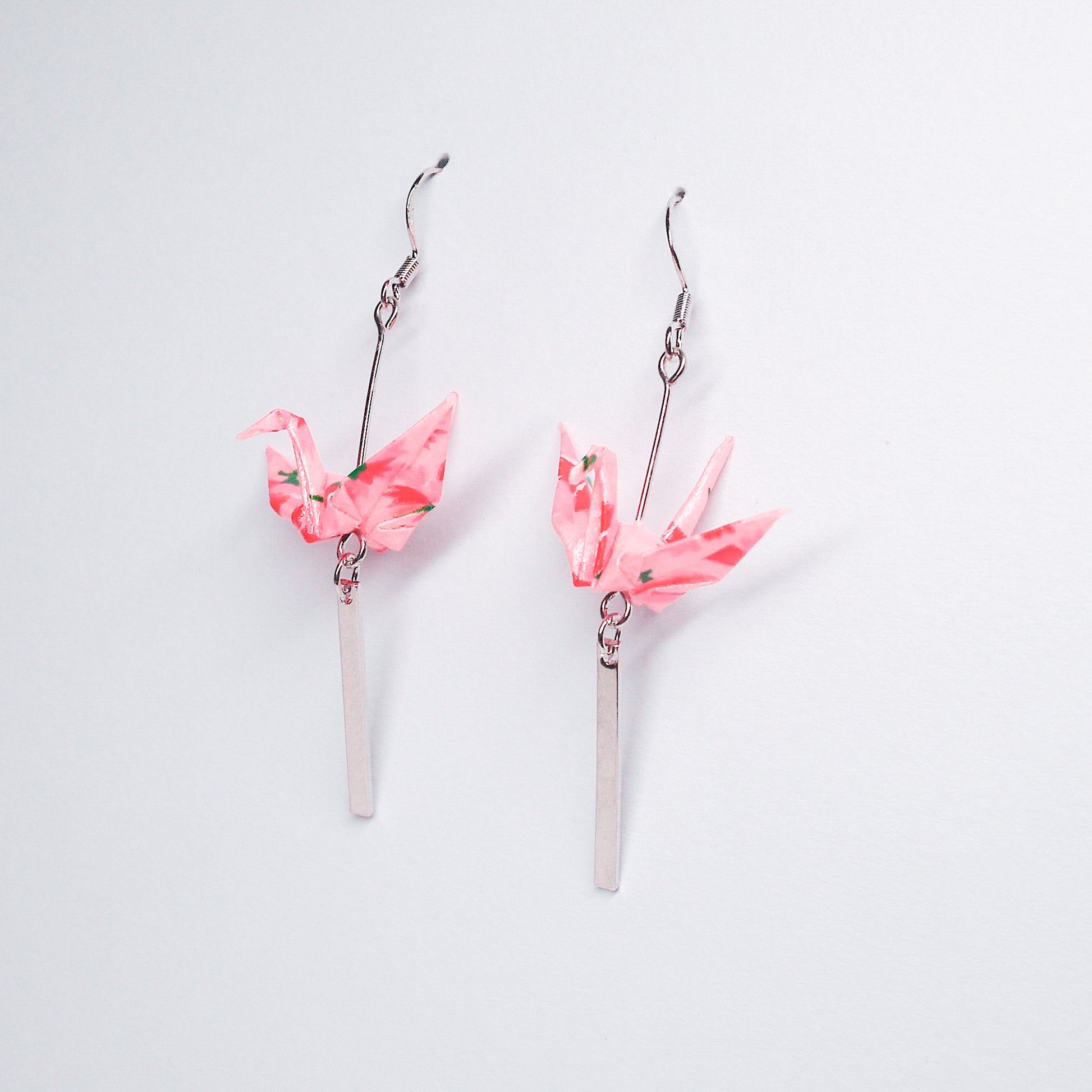 Pair of handmade pink origami crane earrings with silver bar accents and hooks, crafted from traditional Japanese washi paper