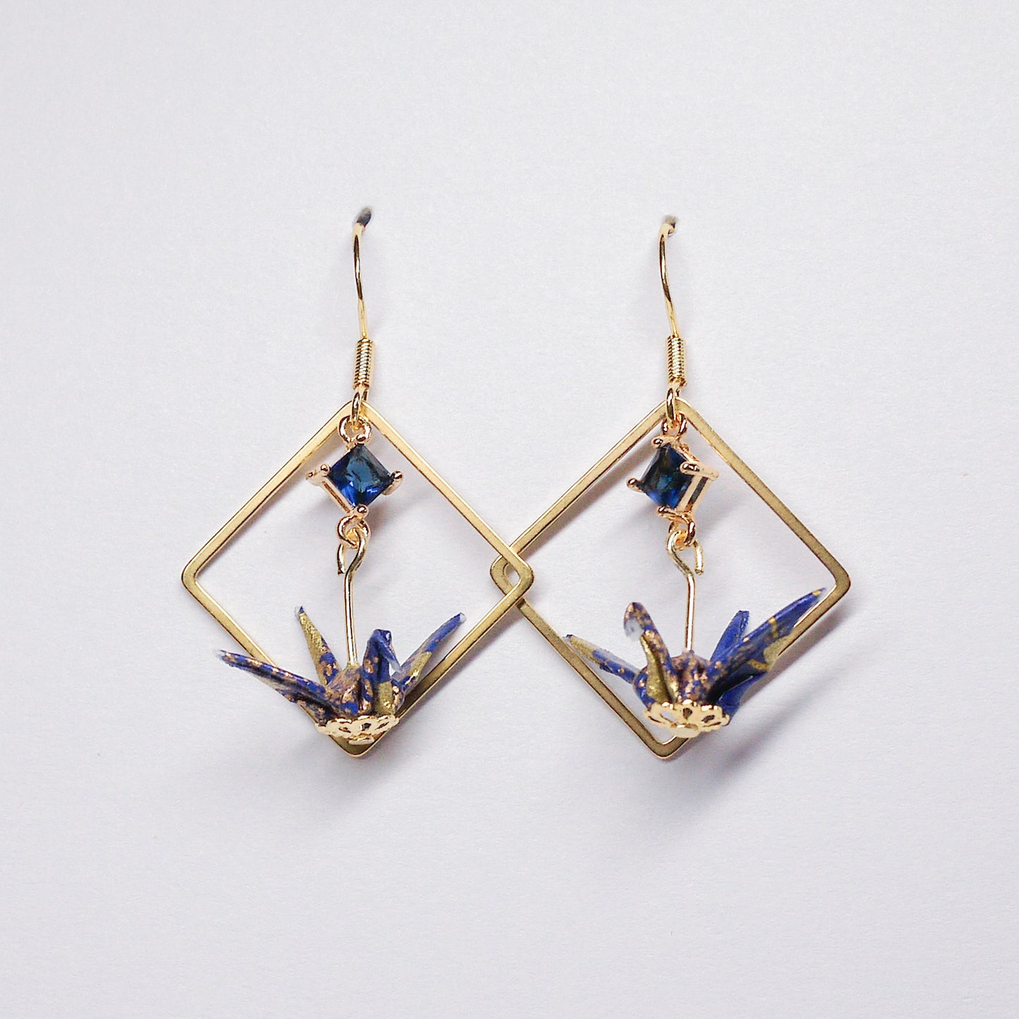 Pair of handmade blue origami crane earrings with gold square hoops and sparkling zircon accents, crafted from traditional Japanese washi paper.