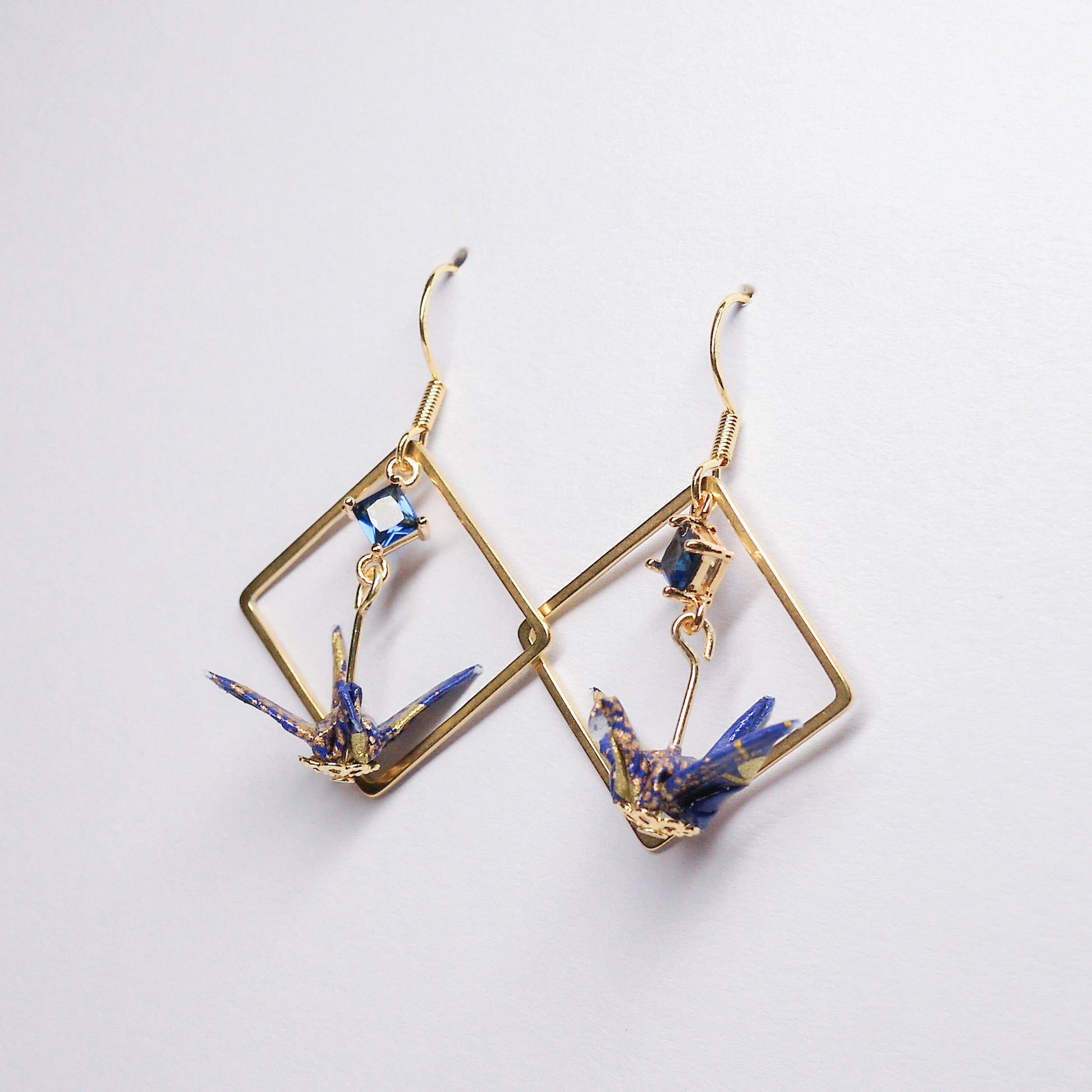 Pair of handmade blue origami crane earrings with gold square hoops and sparkling zircon accents, crafted from traditional Japanese washi paper.