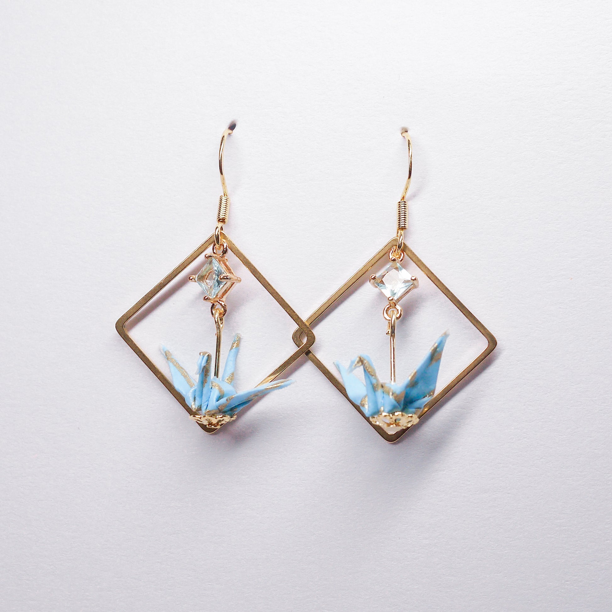 Pair of handmade teal origami crane earrings with gold square hoops and sparkling zircon accents, crafted from traditional Japanese washi paper.