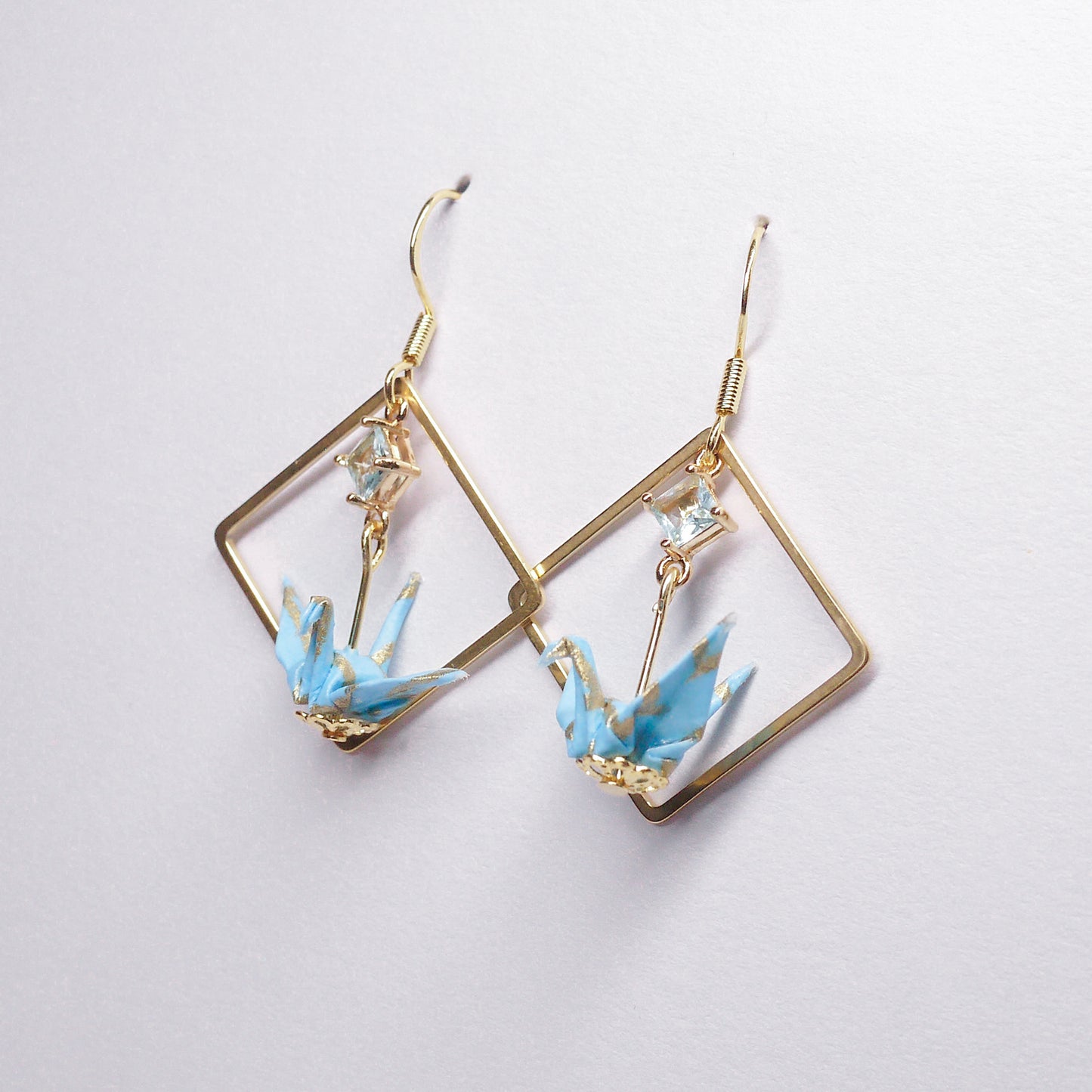 Pair of handmade teal origami crane earrings with gold square hoops and sparkling zircon accents, crafted from traditional Japanese washi paper.