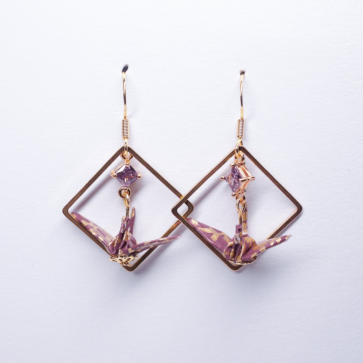 Pair of handmade purple origami crane earrings with gold square hoops and sparkling zircon accents, crafted from traditional Japanese washi paper.