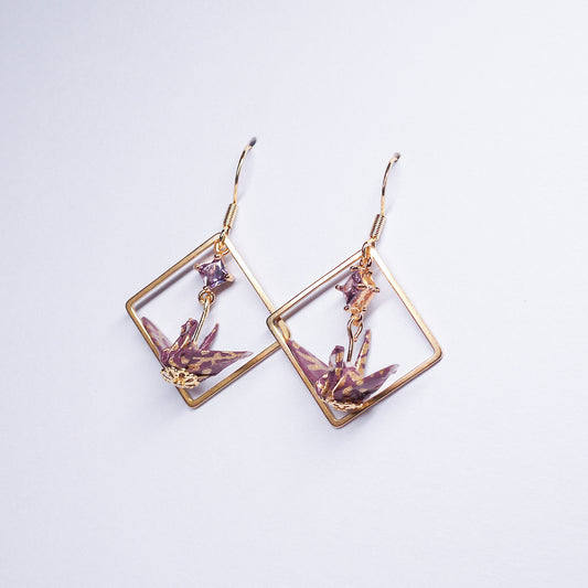 Pair of handmade purple origami crane earrings with gold square hoops and sparkling zircon accents, crafted from traditional Japanese washi paper.