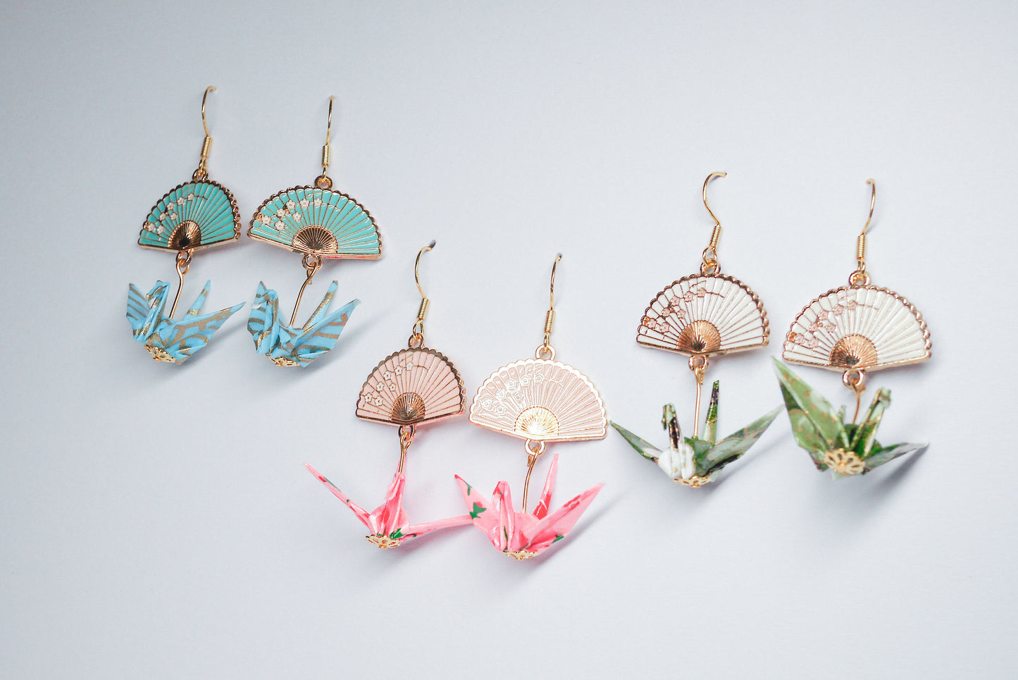 Collection of handmade origami crane earrings in various colors, featuring gold hooks and delicate paper cranes crafted from traditional Japanese washi paper.