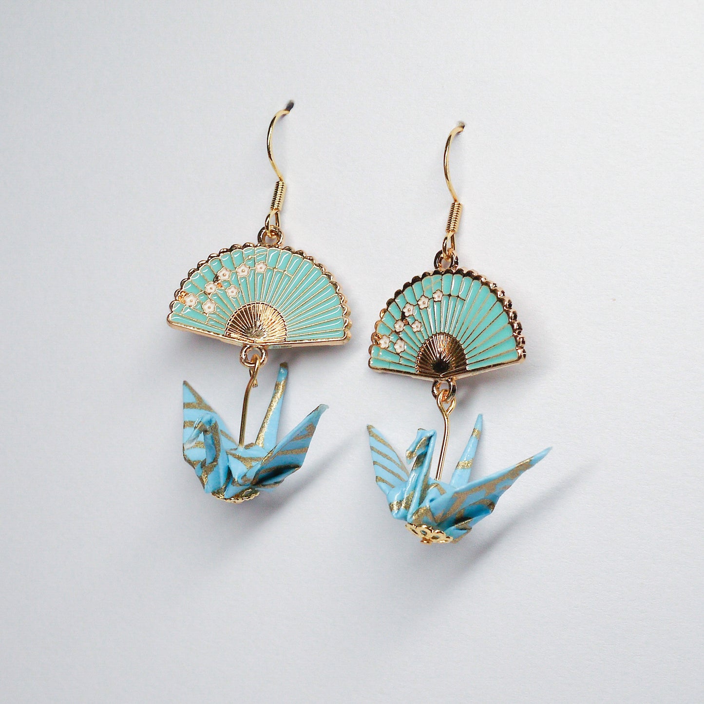 Pair of handmade teal origami crane earrings with gold fan charms and hooks, crafted from traditional Japanese washi paper