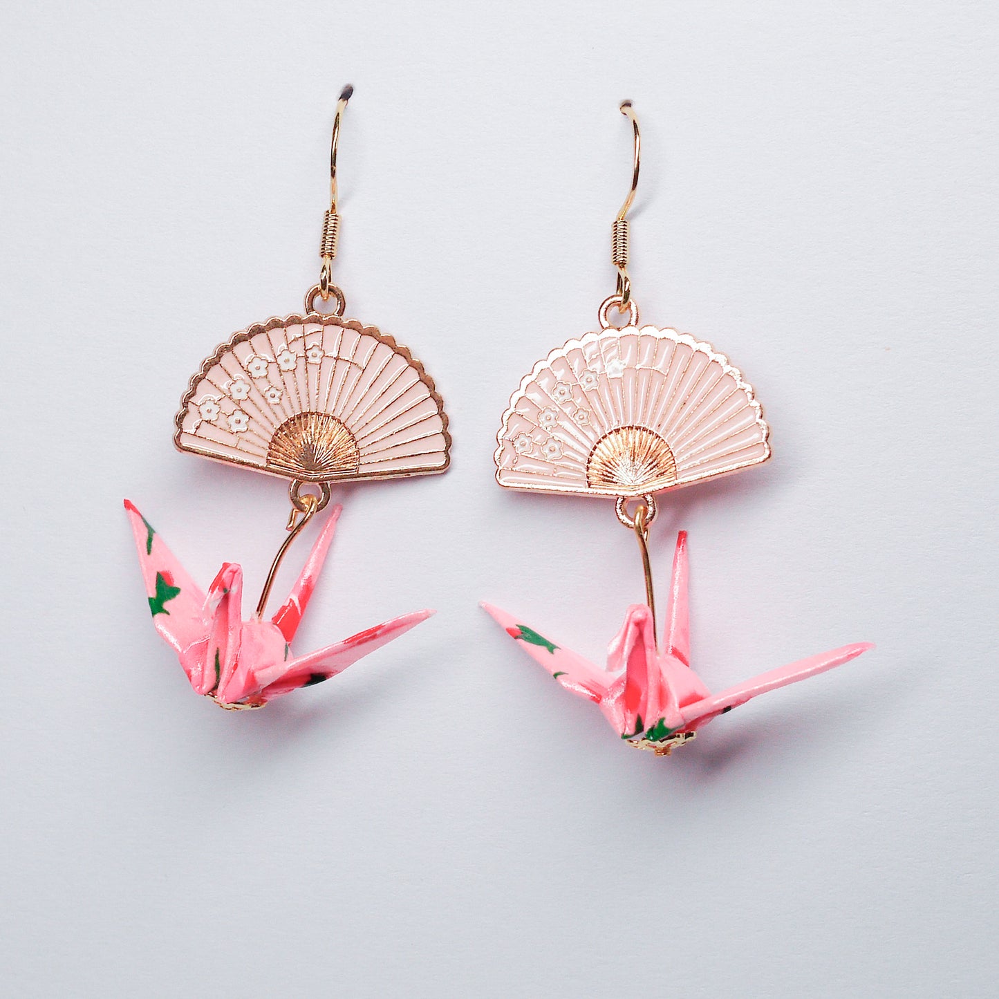 Pair of handmade pink origami crane earrings with gold fan charms and hooks, crafted from traditional Japanese washi paper