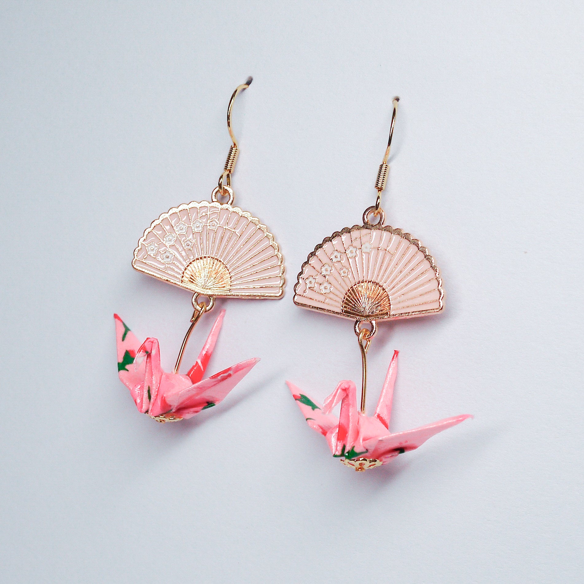 Pair of handmade pink origami crane earrings with gold fan charms and hooks, crafted from traditional Japanese washi paper