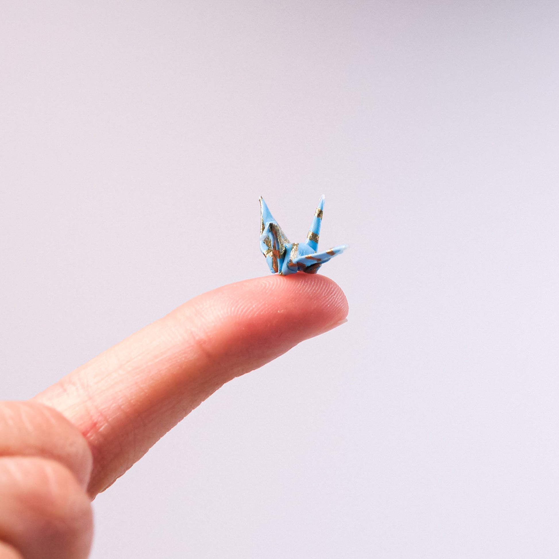 tiny paper crane on a fingertip