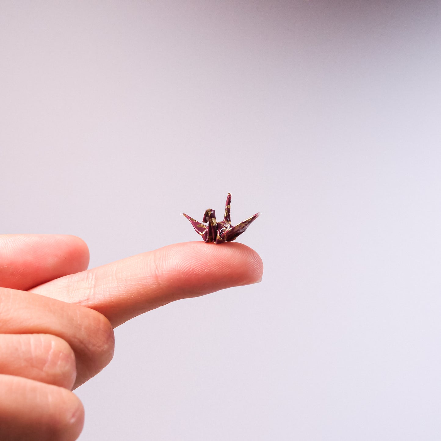 tiny paper crane on fingertip