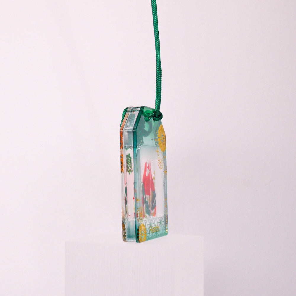 Small rectangular pendant with a green cord on a white background