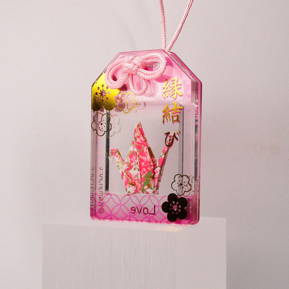 Pink decorative tag with cartoon flowers on a white pedestal against a light gray background